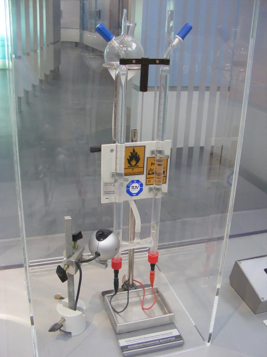 A Hofmann voltameter in a museum case: two tall glass tubes with electrodes at the bottom, used to split water into hydrogen and oxygen