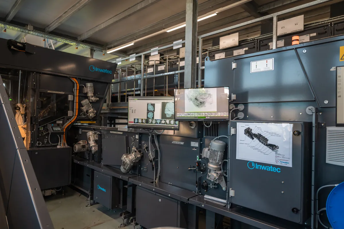 Robotic arms and screens on an Inwatec machine that sorts linen inside an industrial laundry
